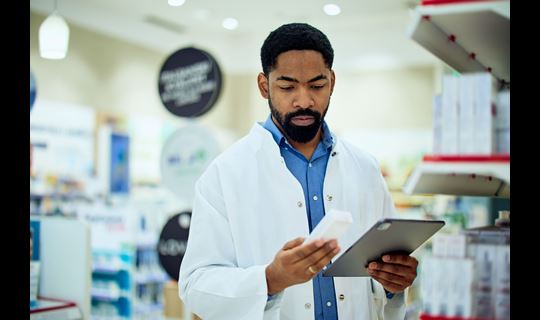 man in lab coat examines medicine box