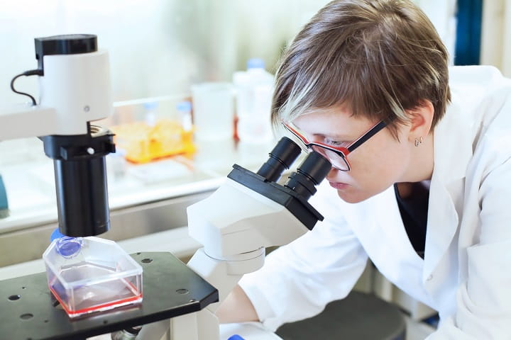 woman looking through microscope