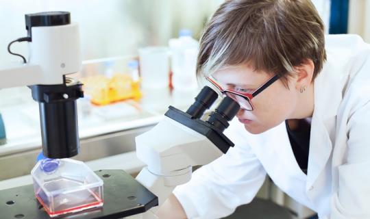 woman looking through microscope