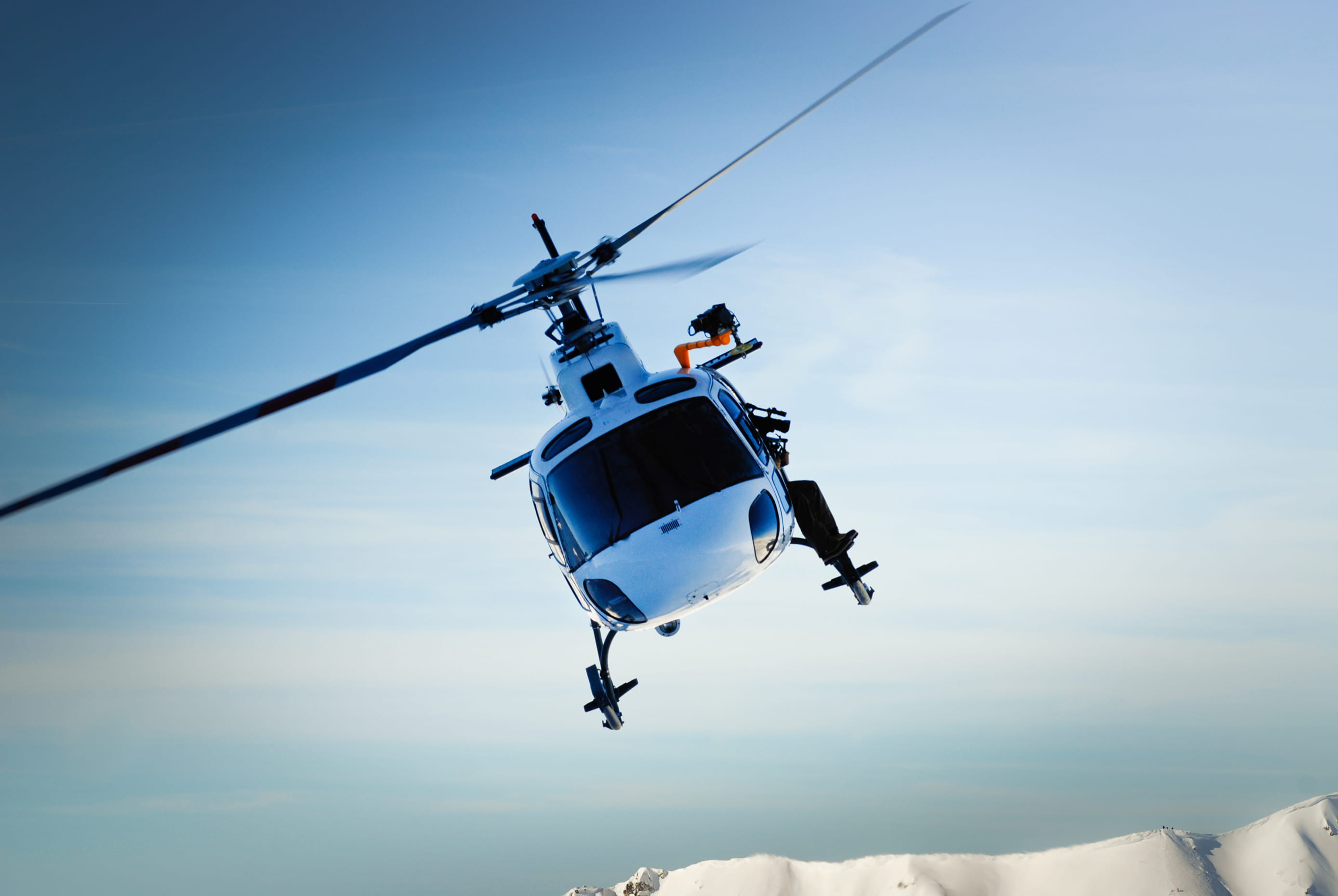A helicopter flies with a clear sky in the background.