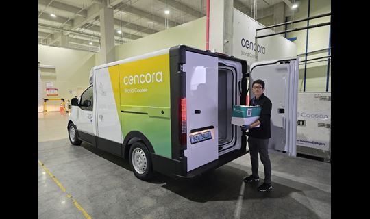 Picture of man holding box for delivery next to sustainable electric delivery van