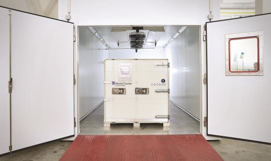 A cocoon shipping container sits inside a large climate chamber inside CORE Labs.