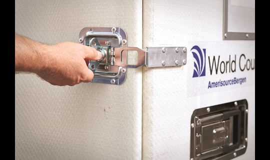 A hand reaches to unlatch a World Courier shipping container.