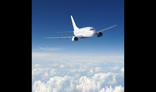 A wide view of an airplane flying over the clouds.
