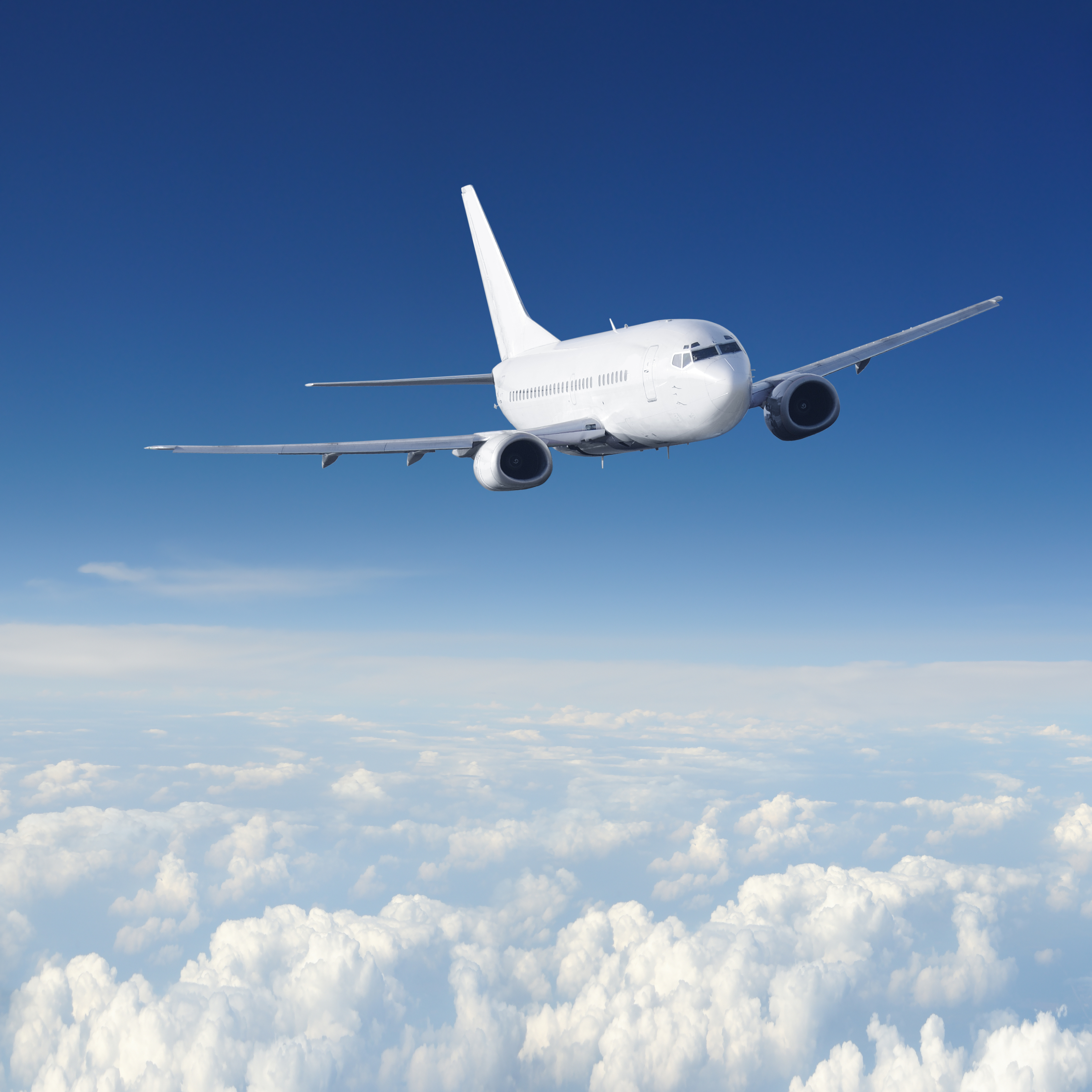 A wide view of an airplane flying over the clouds.